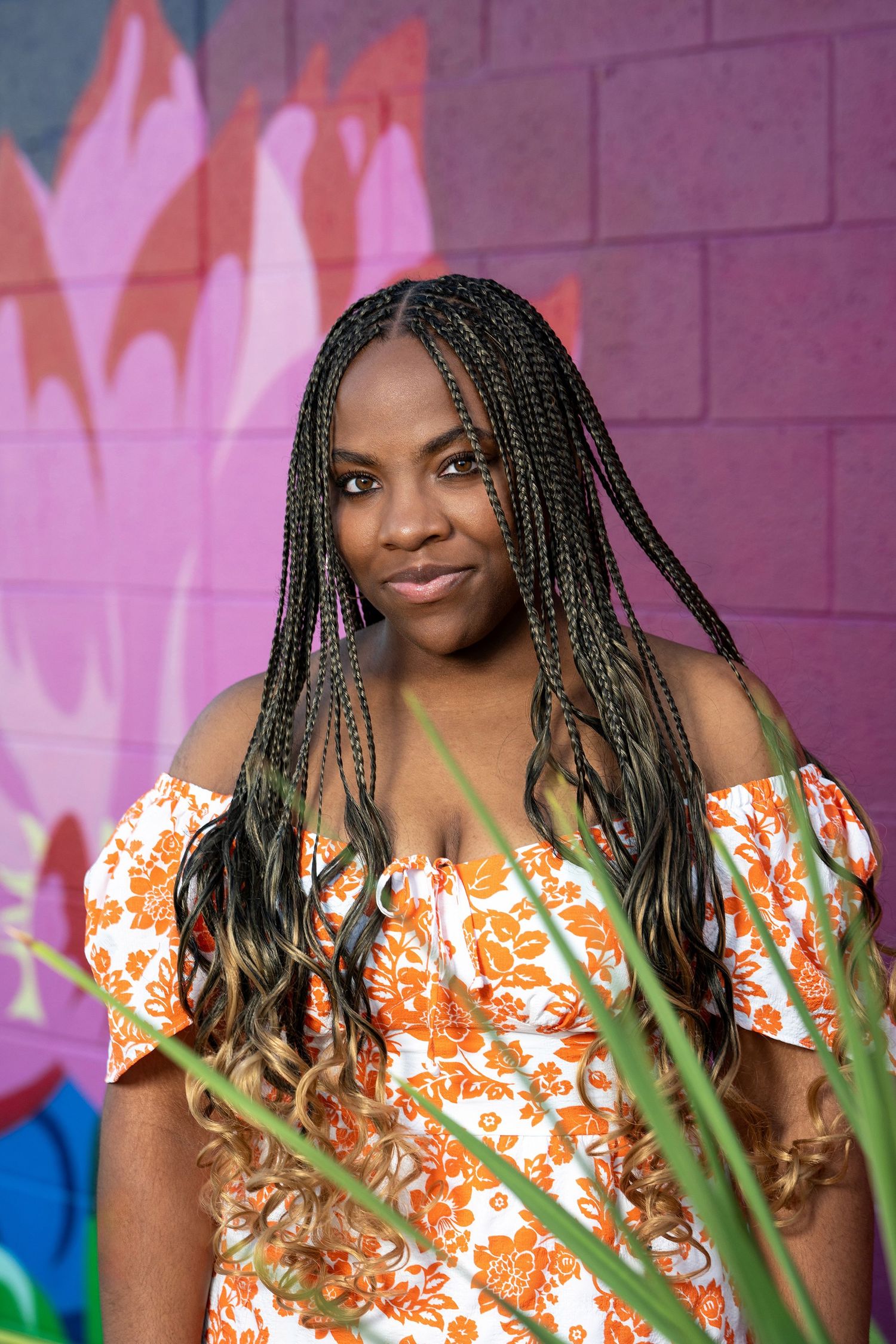 A portrait session featuring a floral orange dress against a colorful street art backdrop.