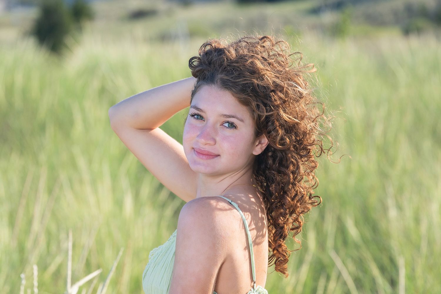 A summer portrait in soft lighting with beach grass and blue skies in the background.
