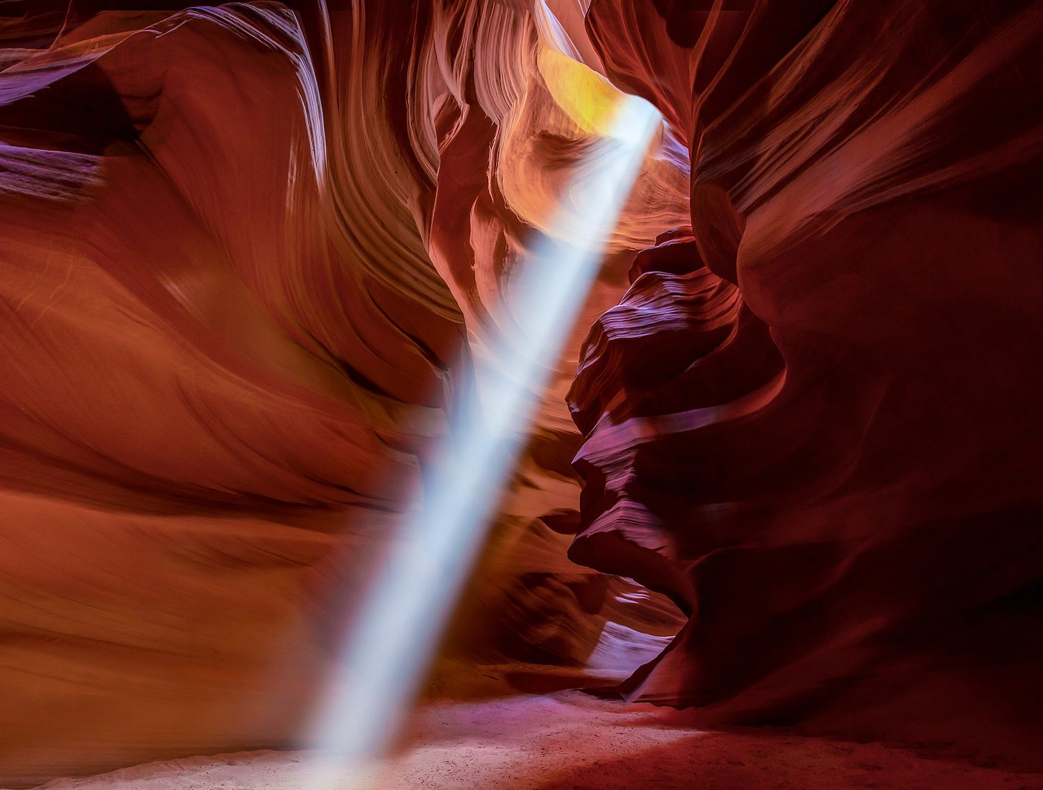 Light beams streaming through red rock formations in Antelope Canyon.