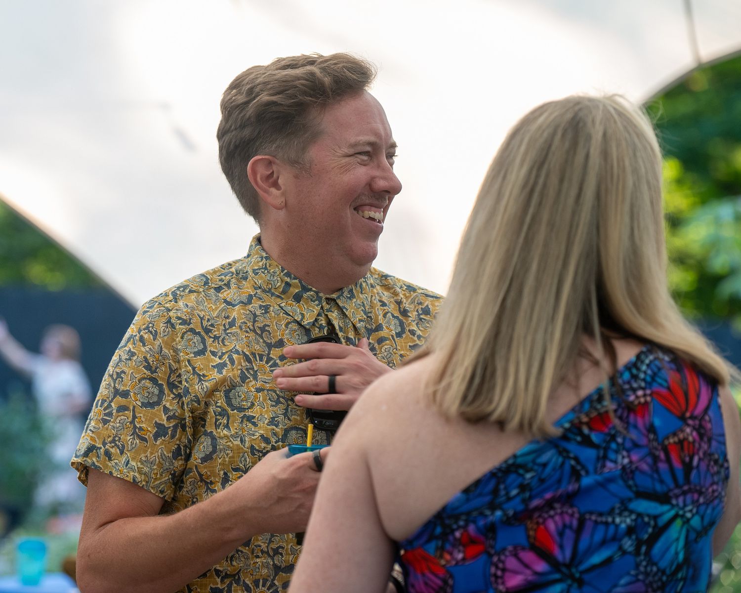 A couple in colorful attire sharing a joyful moment at an outdoor event.