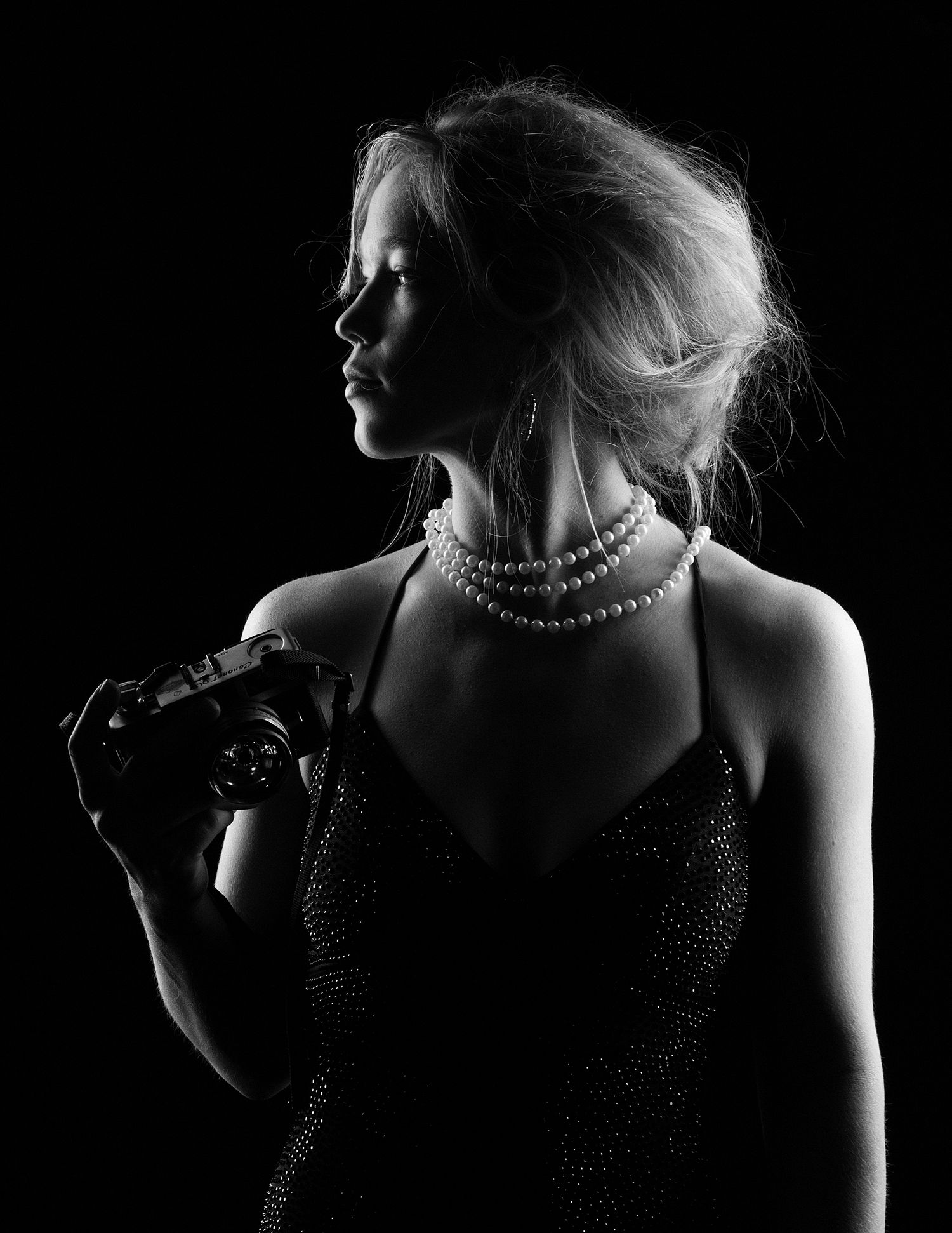 Artistic black and white portrait showing necklace and shoulder details.