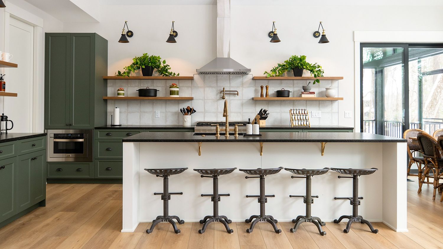 Contemporary kitchen featuring sage green cabinets, industrial bar stools, and open shelving with pendant lights.