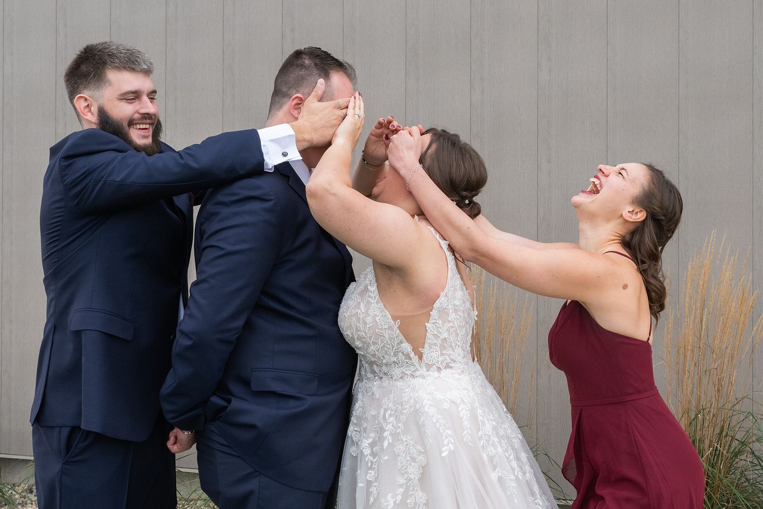 Wedding party playfully covers the grooms eyes during a fun outdoor bridal party photo session.