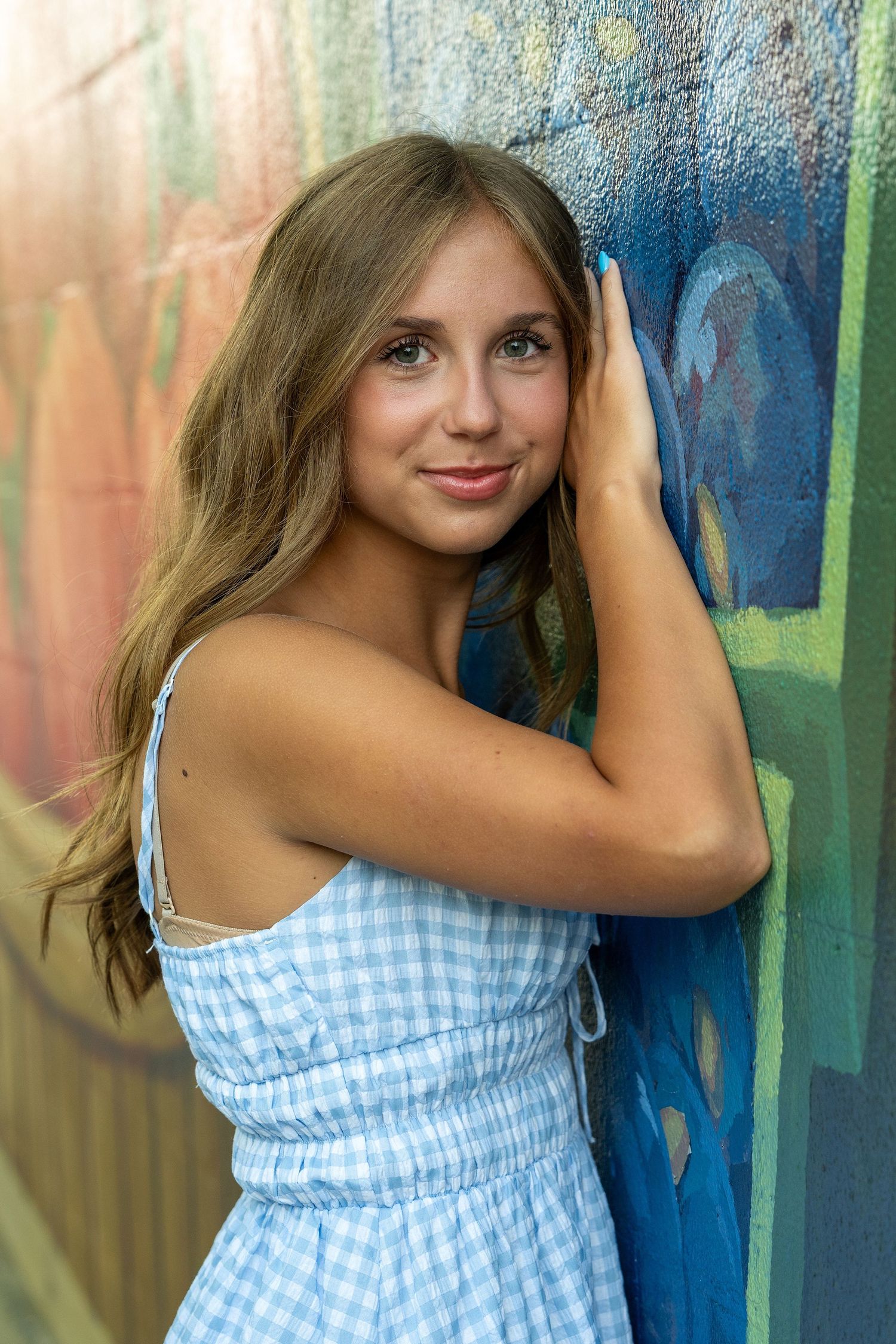 Artistic portrait against colorful painted wall with blue and orange tones.