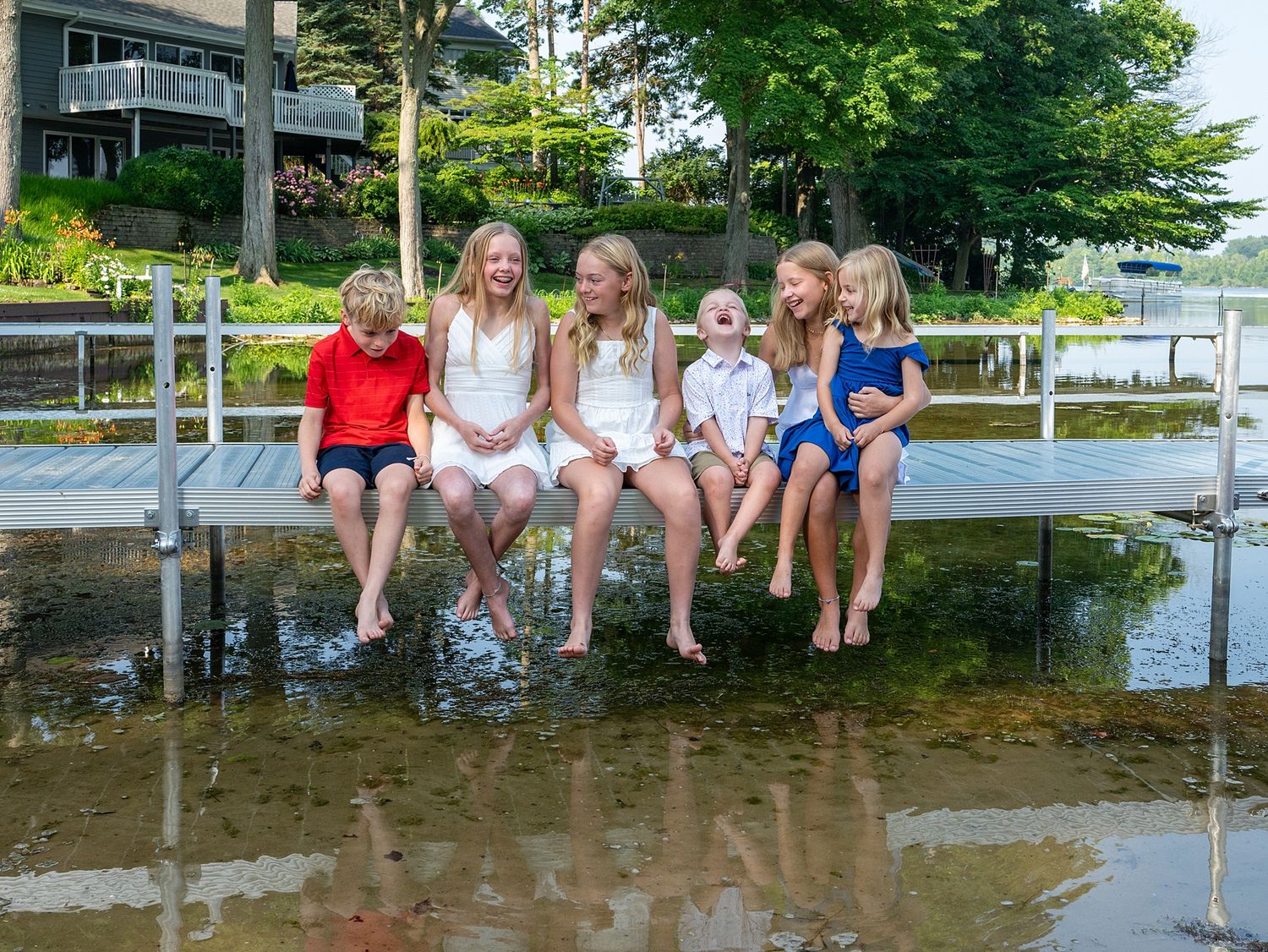 Family members sitting together on a dock over water during summer.