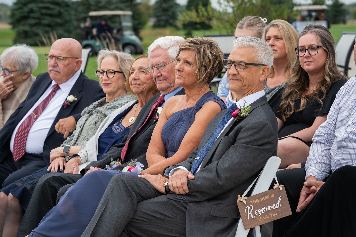 Wedding guests seated in reserved section watching outdoor ceremony on a sunny day.