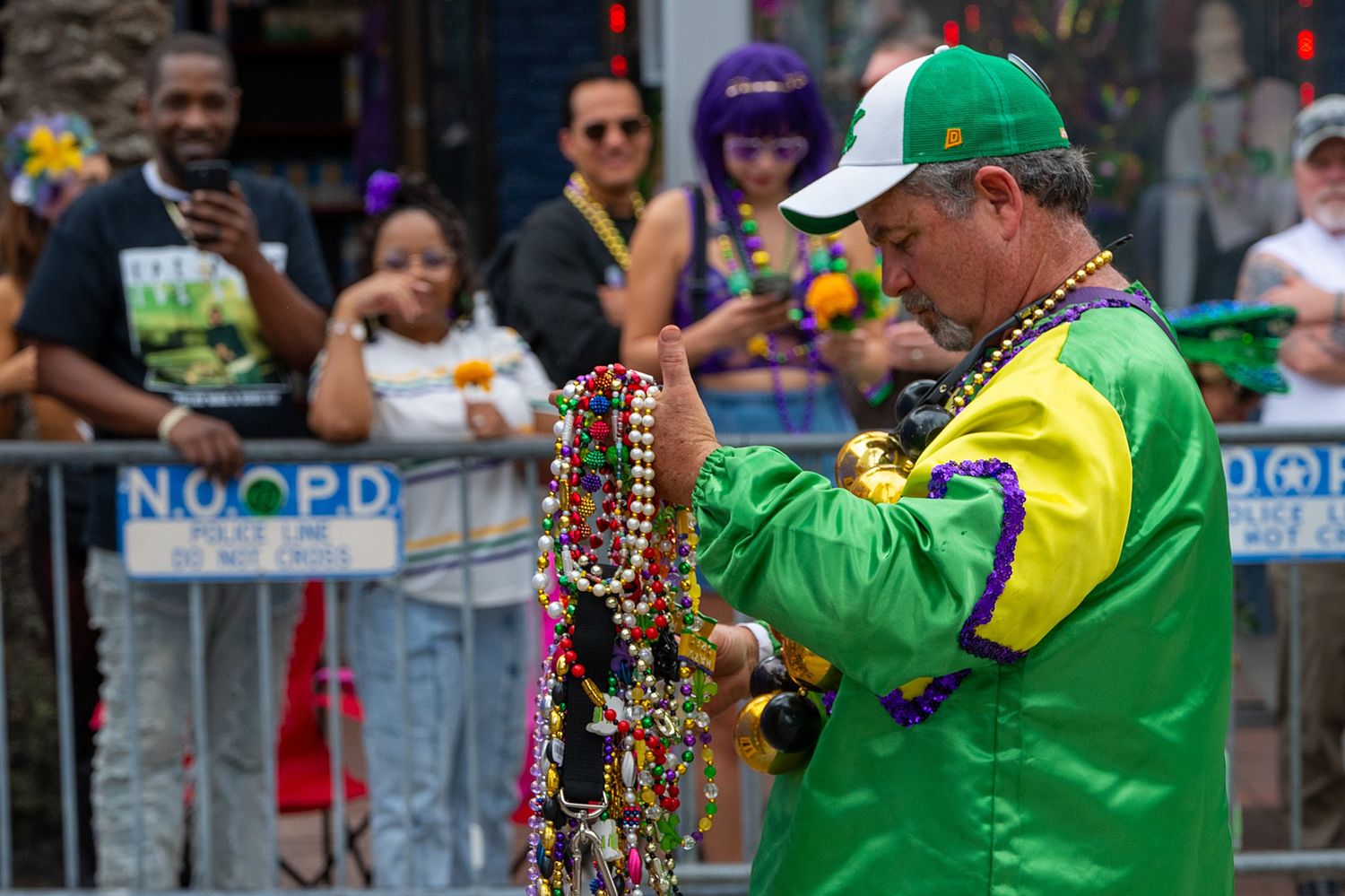 Parade participants wearing green and yellow outfits throwing beads to spectators.