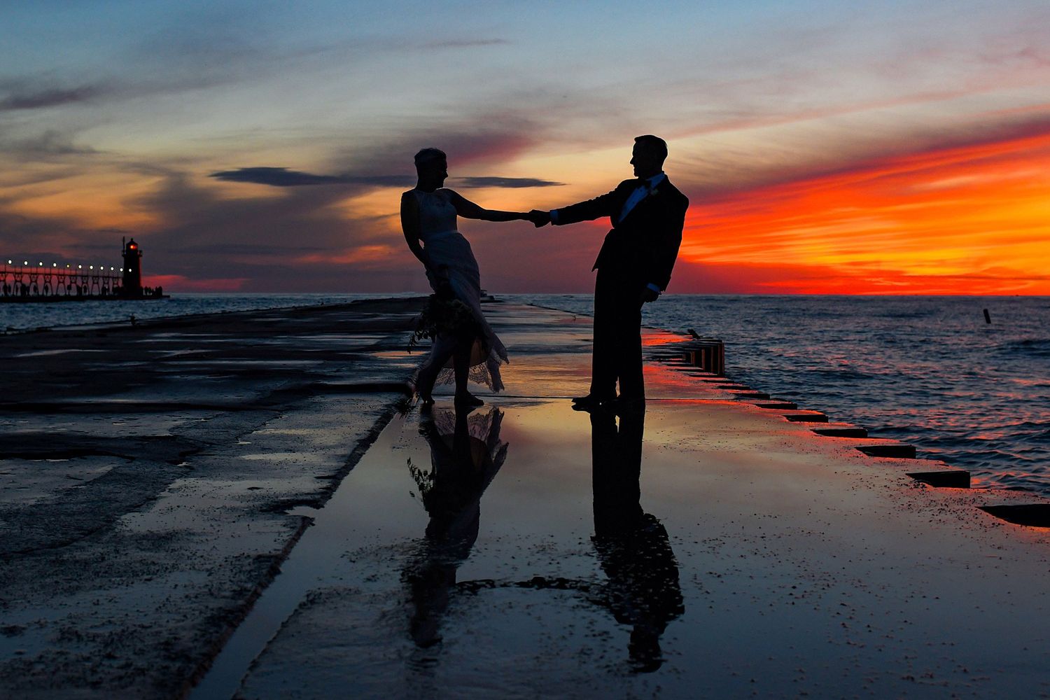 Silhouettes of people on beach at sunset with dramatic orange and purple sky.