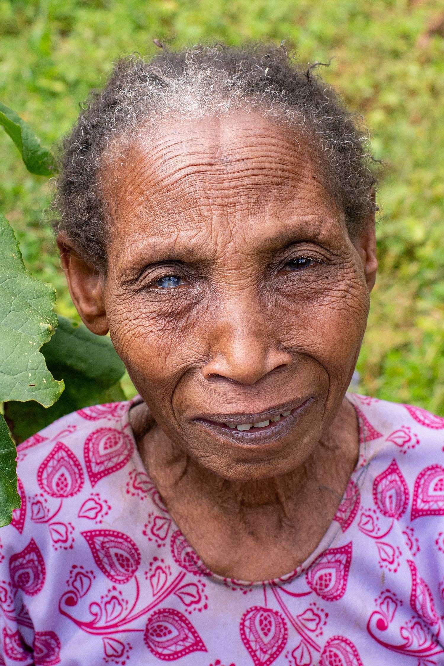 Progressive shots of an elderly woman in a pink patterned shirt smiling against a green background.