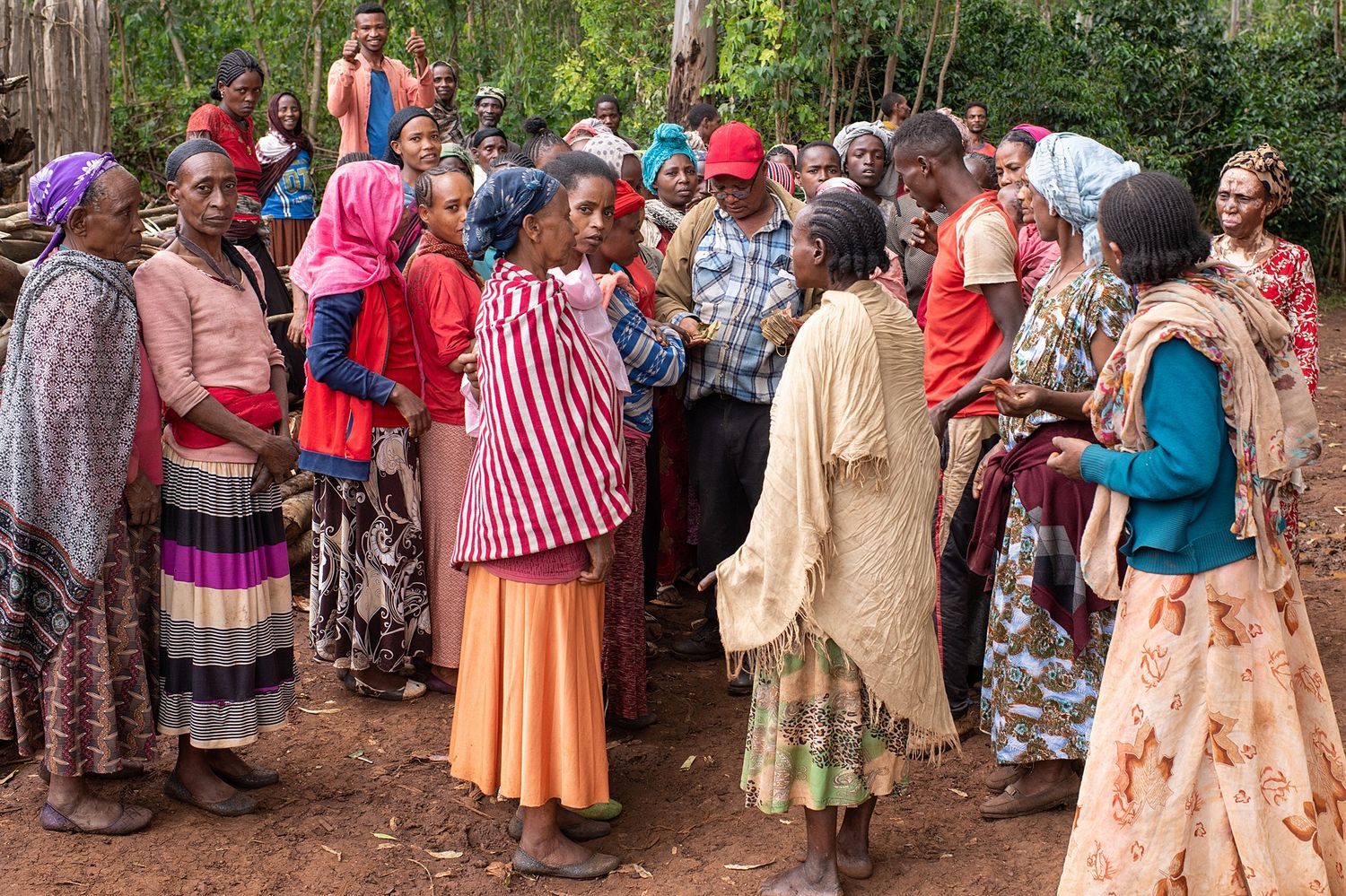 A large gathering of people in colorful traditional dress standing together outdoors.