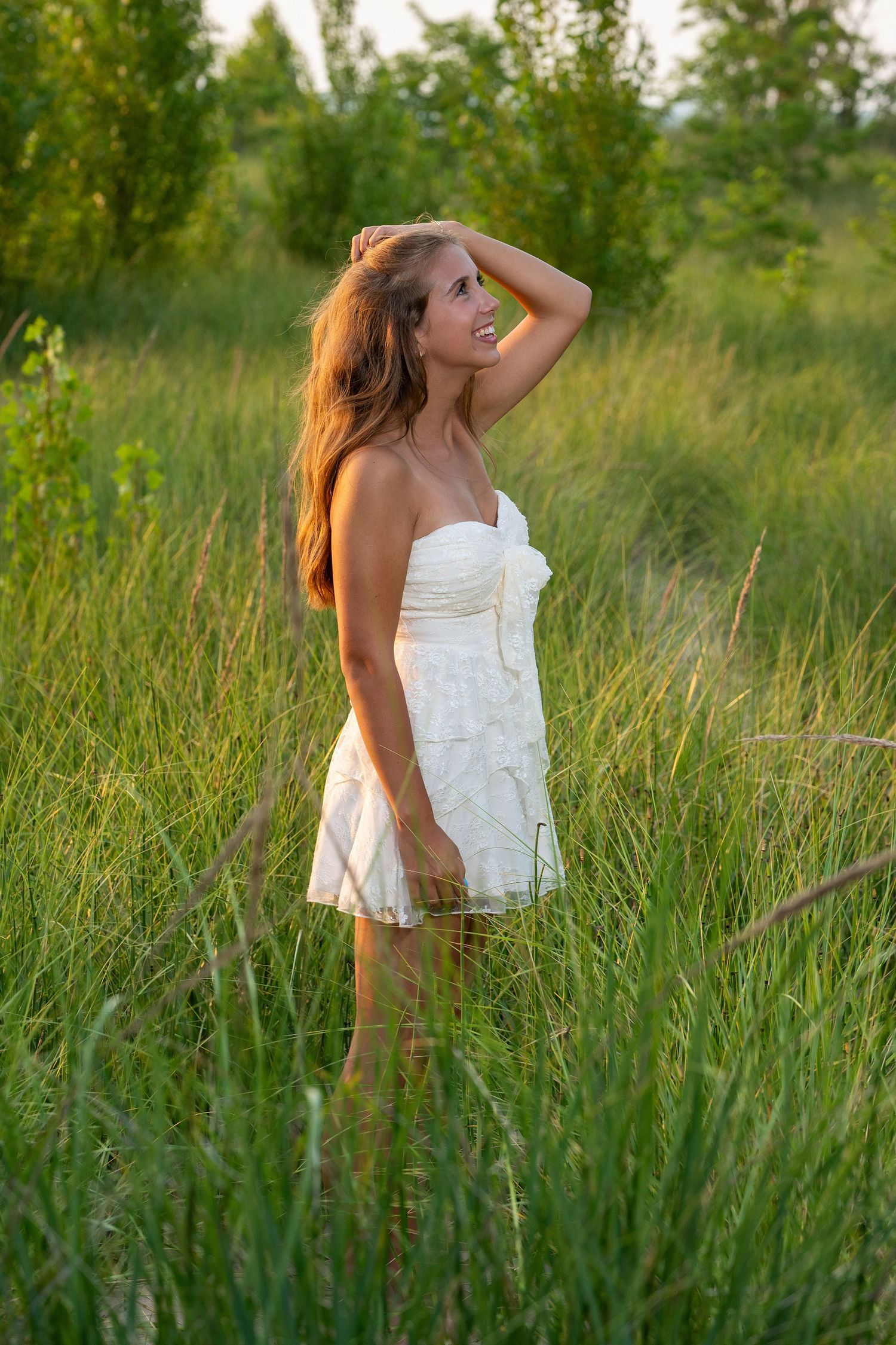 White sundress flowing in tall summer meadow grass during golden hour.