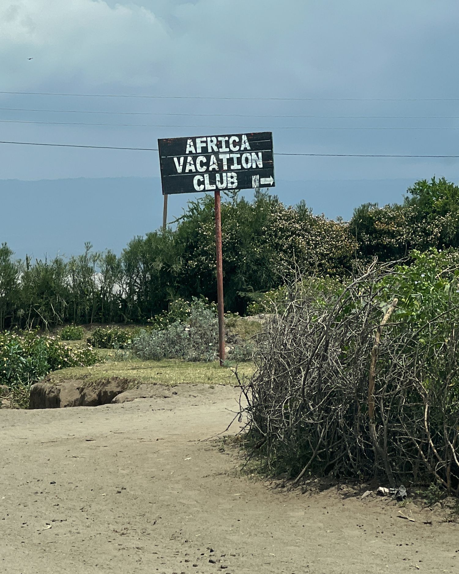 Signs reading 'Africa Vacation Club' along a barren coastal path.