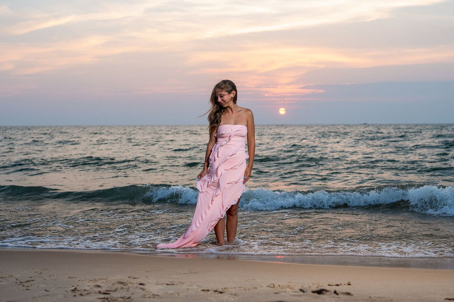 Sunset beach photography session with waves and pink sky in the background.