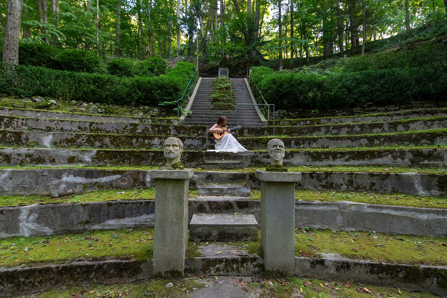 Stone amphitheater steps surrounded by lush green forest.
