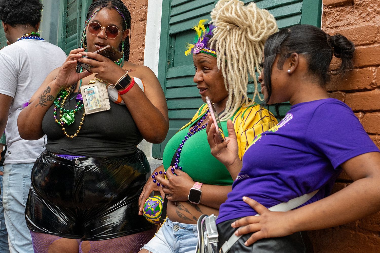 Festive crowd celebrating at Mardi Gras with colorful beads and decorations in New Orleans' French Quarter.
