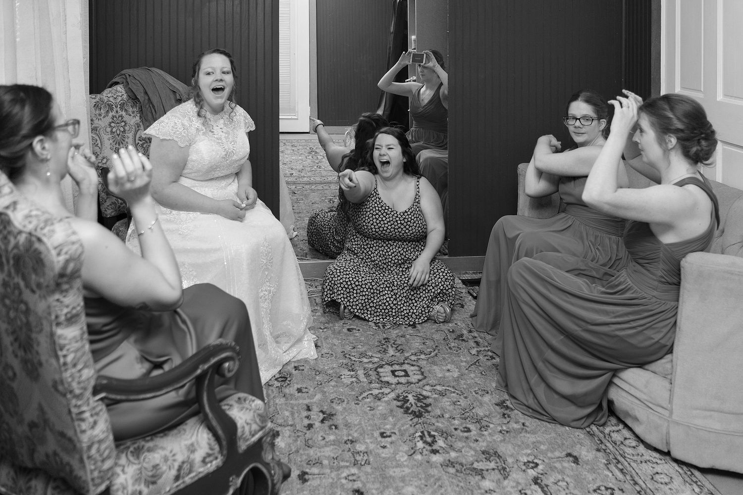 A candid black and white photo capturing joyful laughter during wedding preparations.