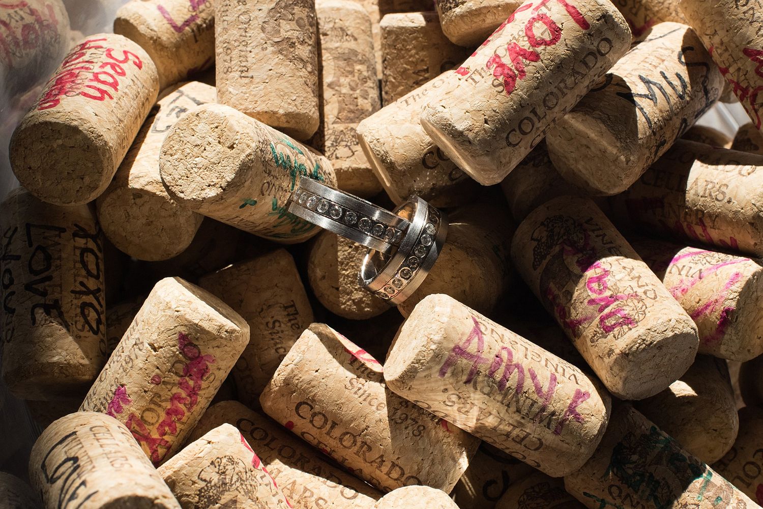 A pile of wine corks with handwritten text, featuring a small ring resting among them.