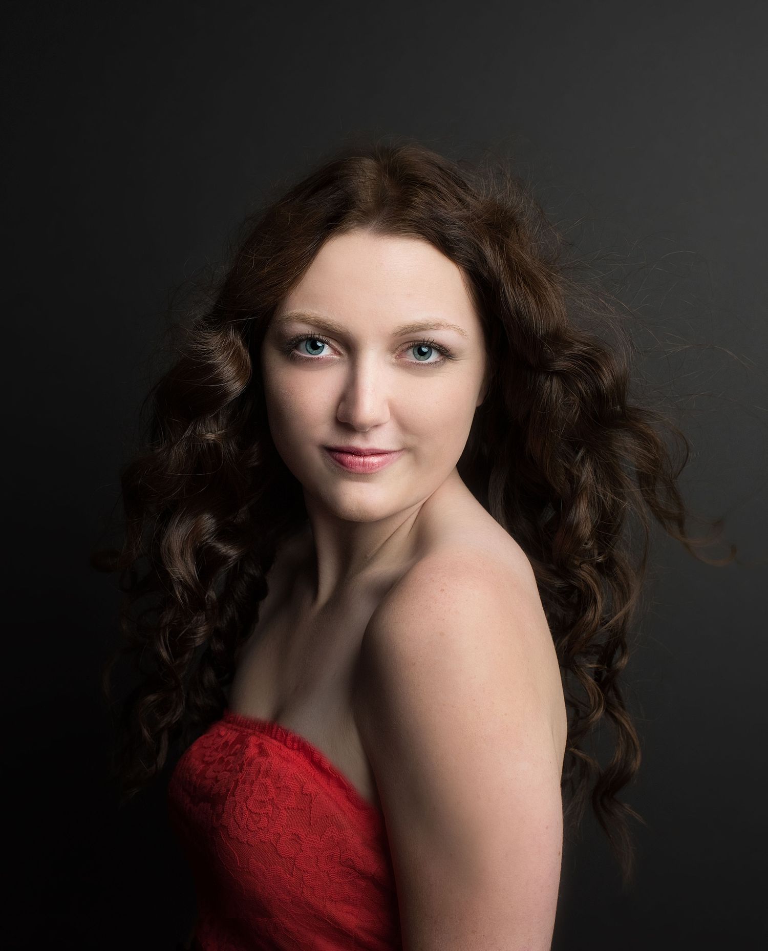 Studio portraits featuring red dress against dark background with dramatic lighting.