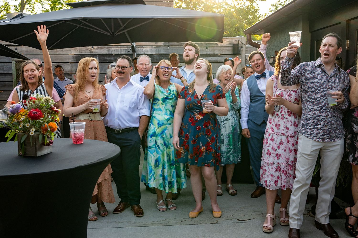 Guests in colorful summer dresses dance and celebrate at an outdoor wedding.