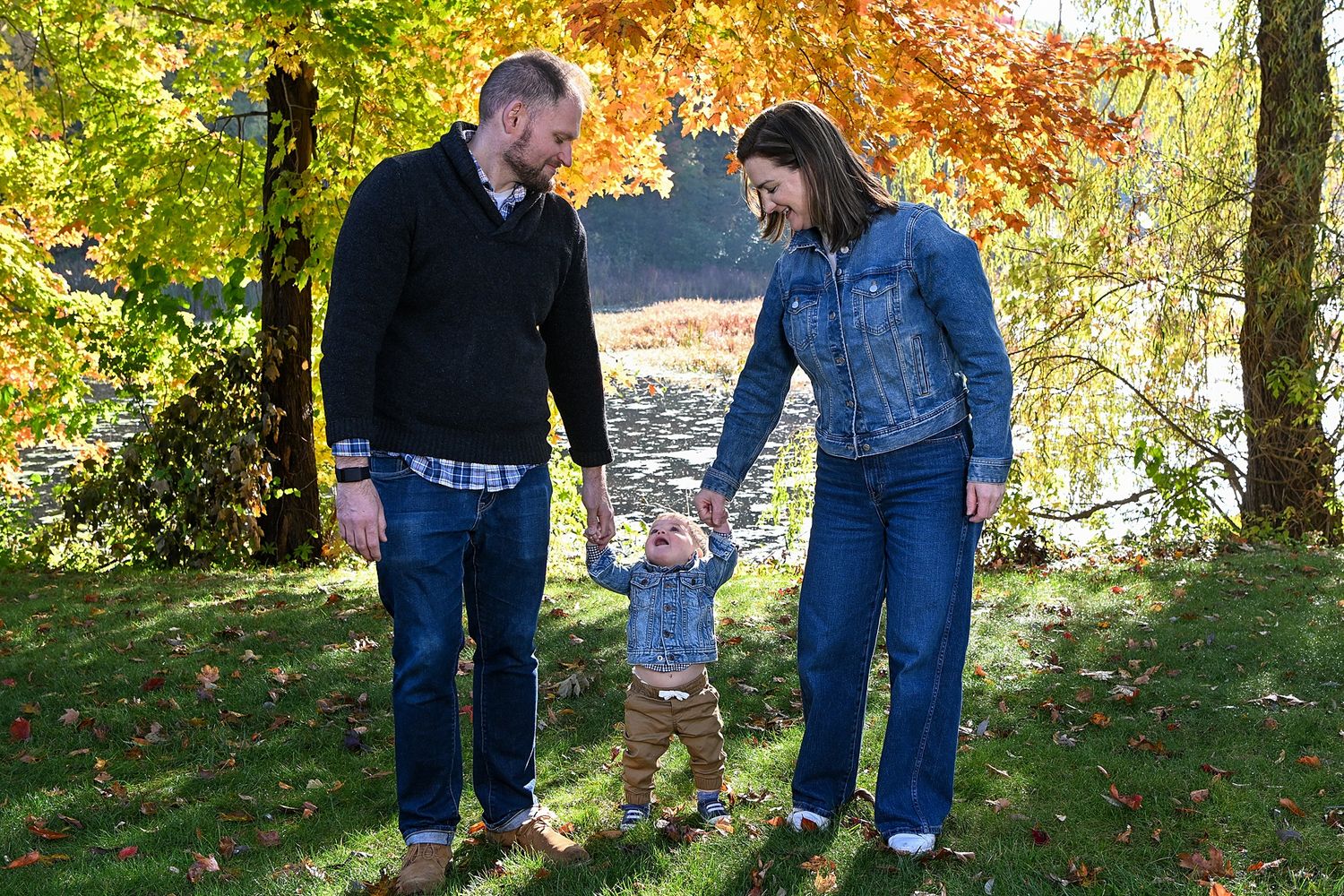 A small family enjoys an autumn day together under colorful trees.
