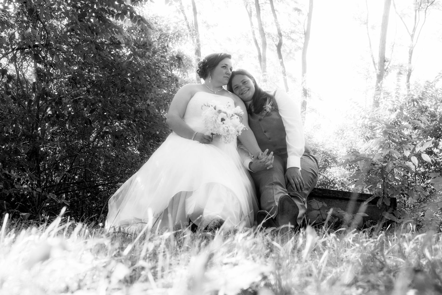 Romantic black and white wedding photos captured in tall grass at sunset.