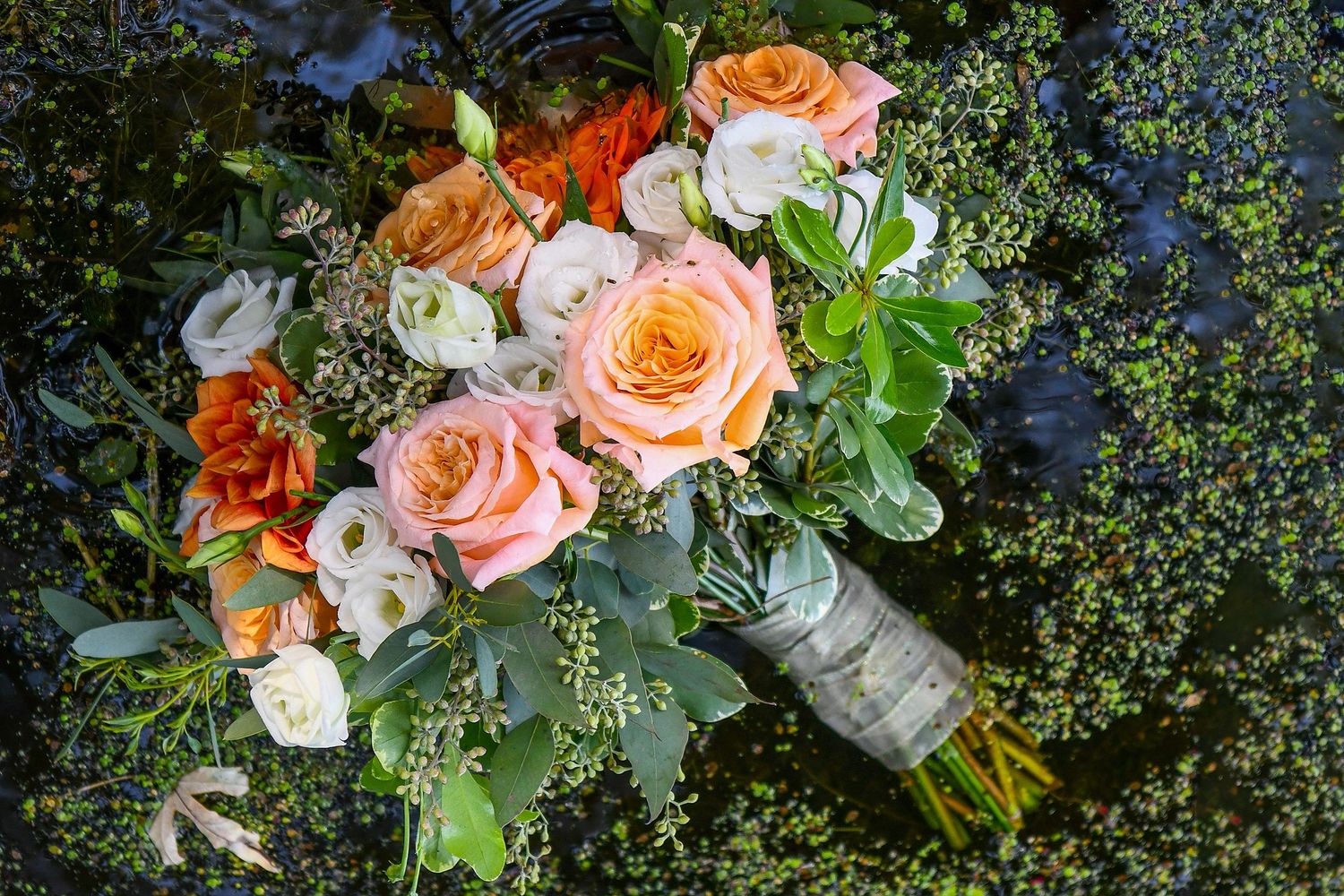 A lush bridal bouquet featuring peach and coral roses with delicate greenery.