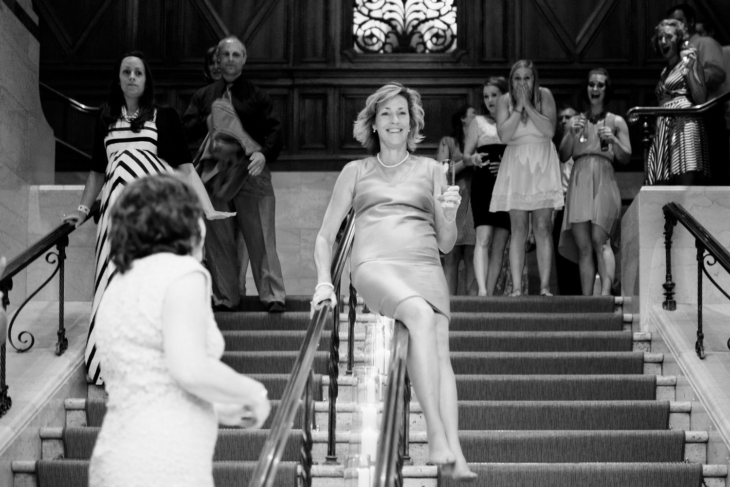 Wedding party descending grand stone steps during outdoor celebration.