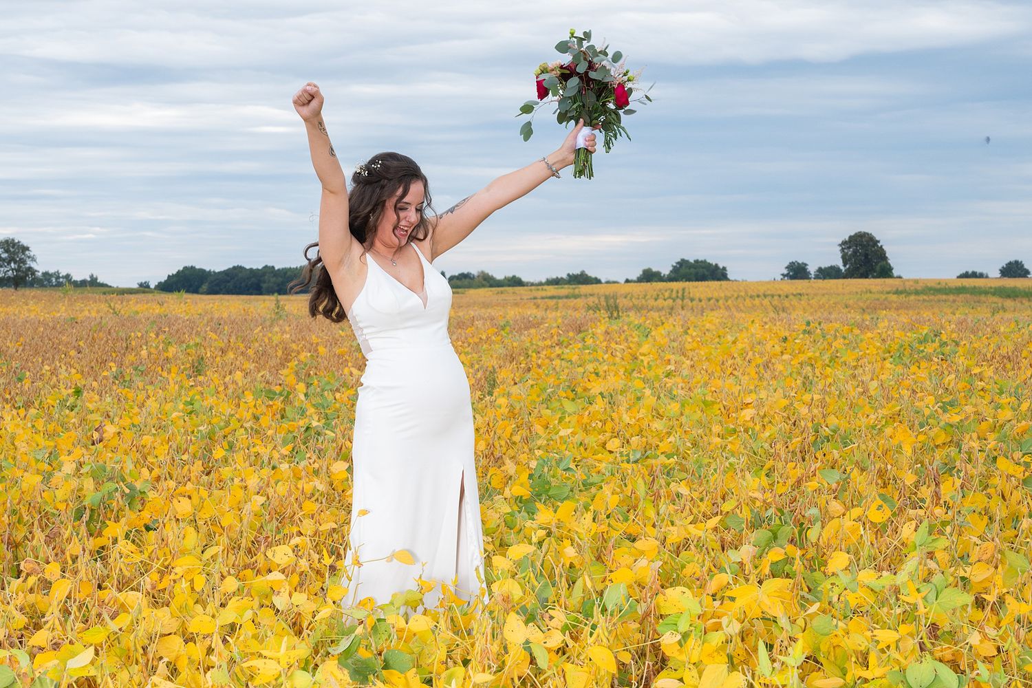 Bride celebrating in a field of bright yellow sunflowers under blue sky.
