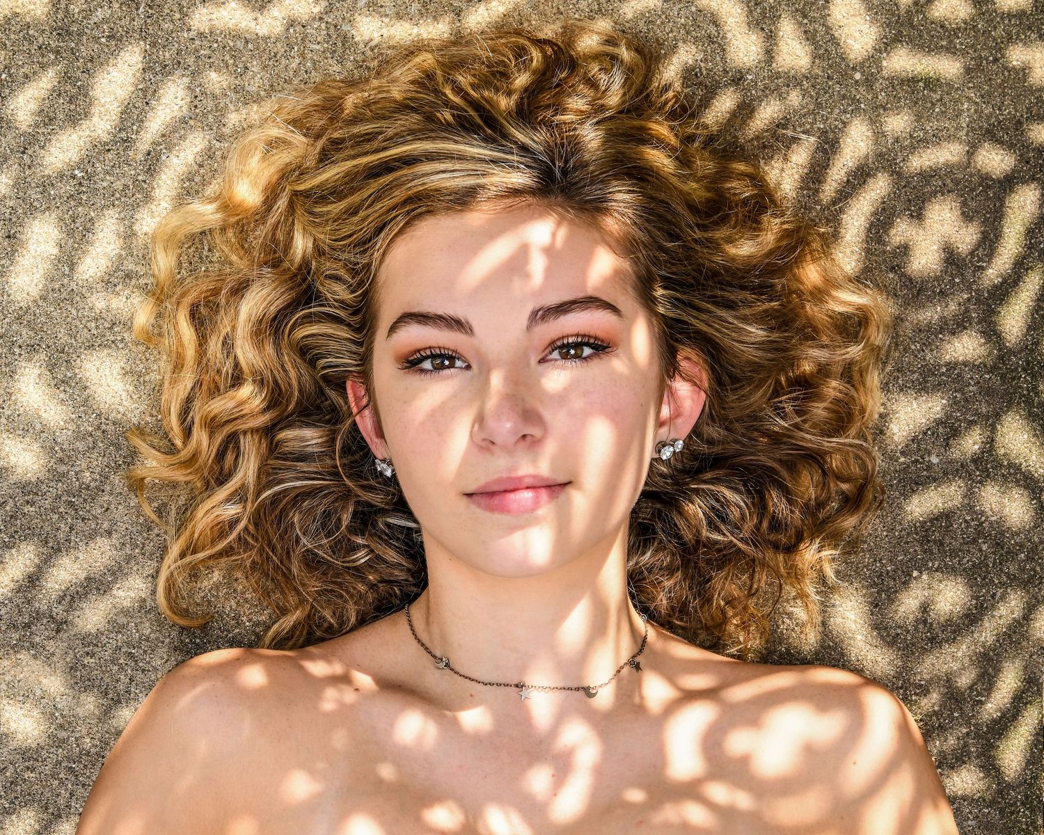 Artistic portrait with dappled shadow patterns creating a dreamy effect.
