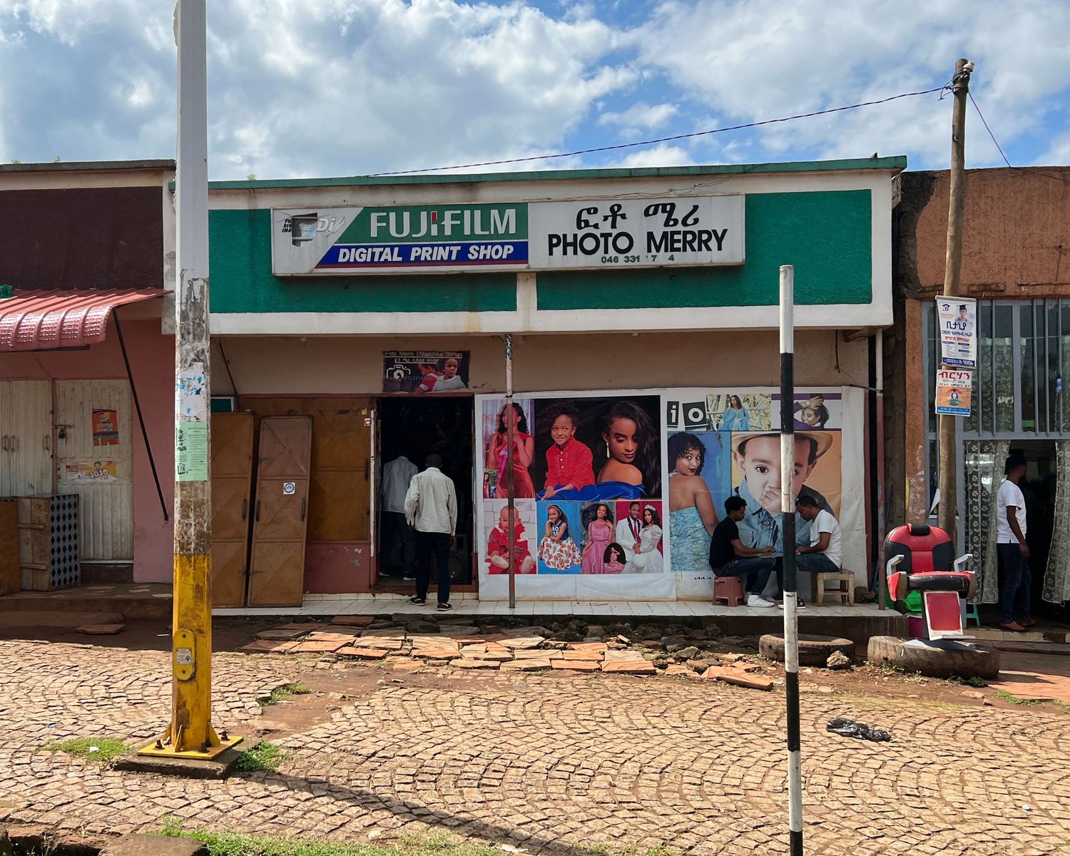 Row of small retail shops and storefronts along a brick paved street.
