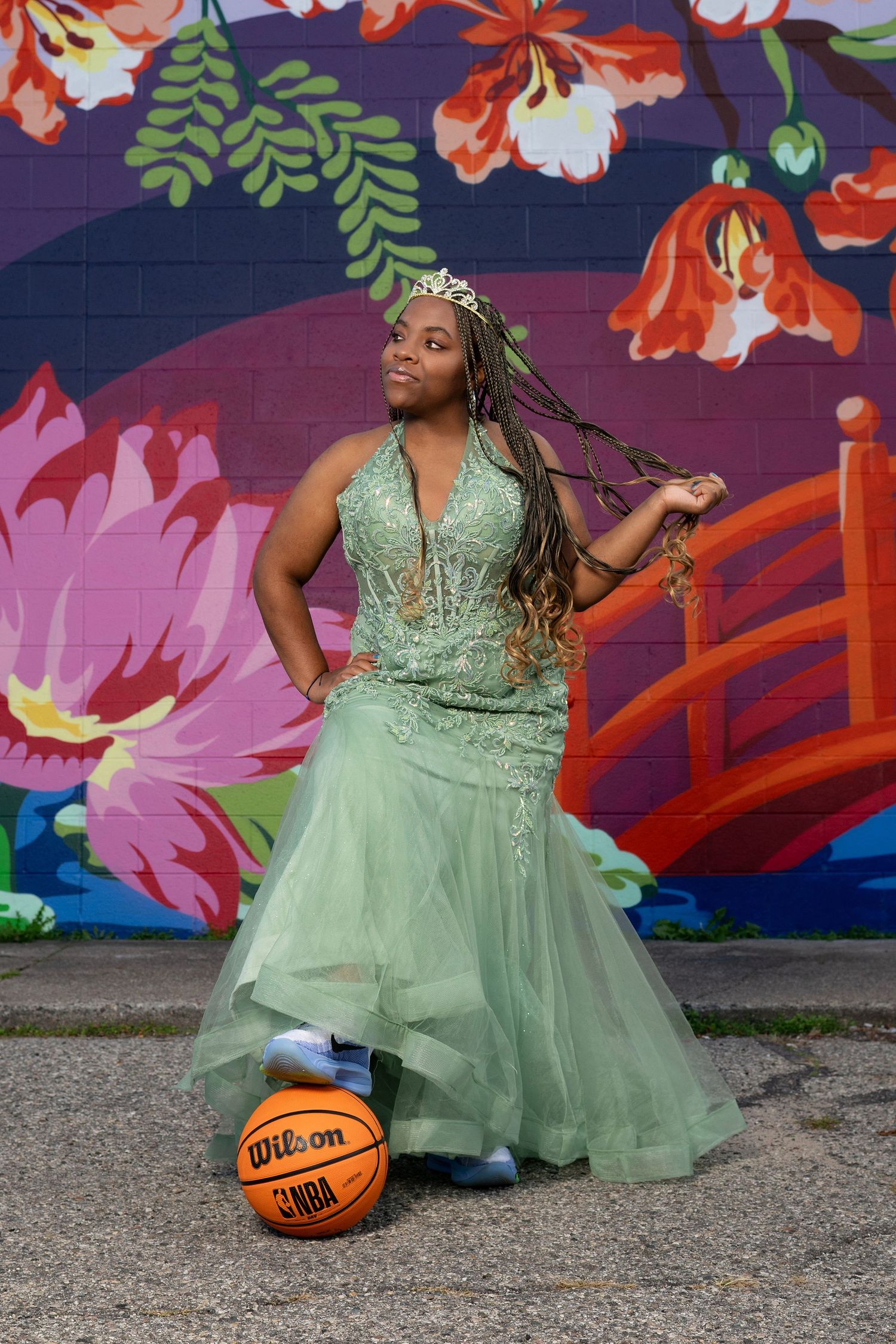 A mint green formal dress photoshoot with a basketball prop against a colorful mural.