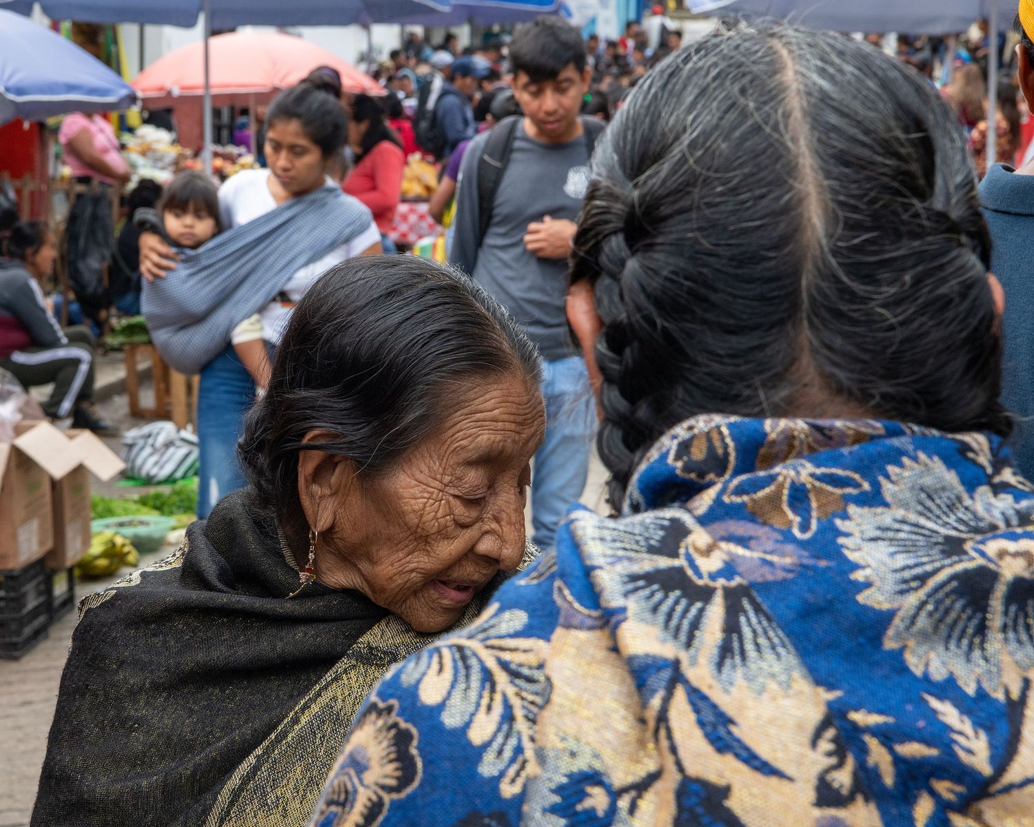 Traditional market scene with vendors displaying goods on blue tarps.