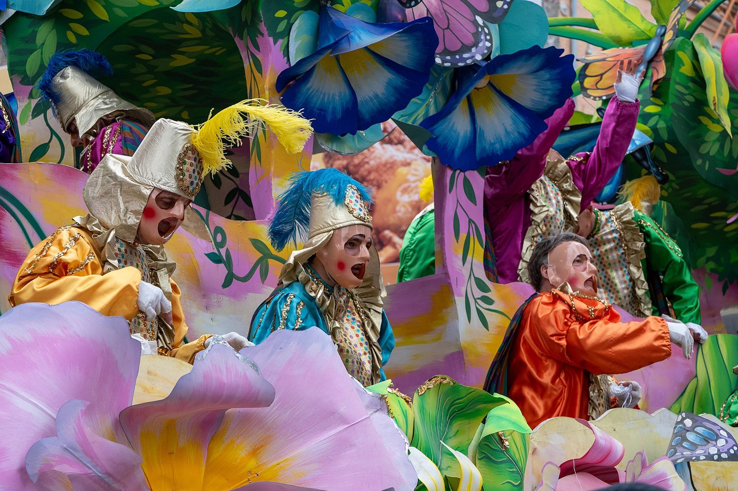 Butterfly and flower themed carnival float with vibrant purple and pink decorations.