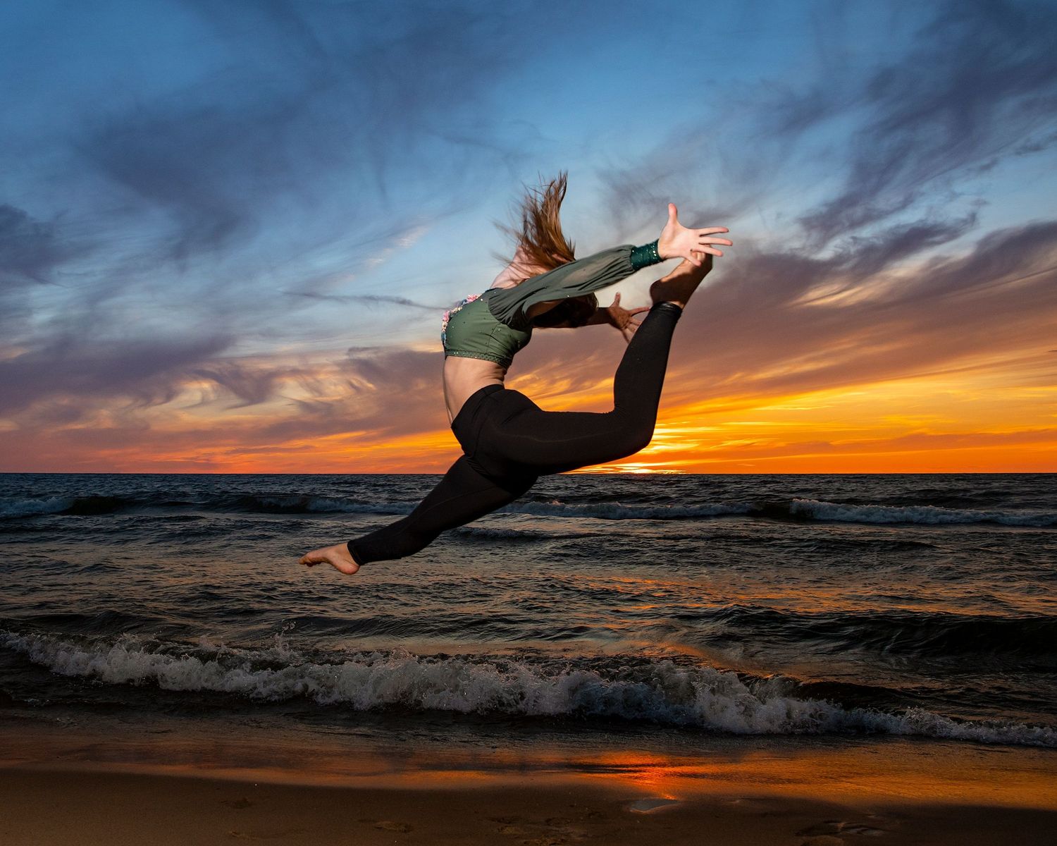 Dramatic silhouette of person leaping against sunset ocean backdrop.
