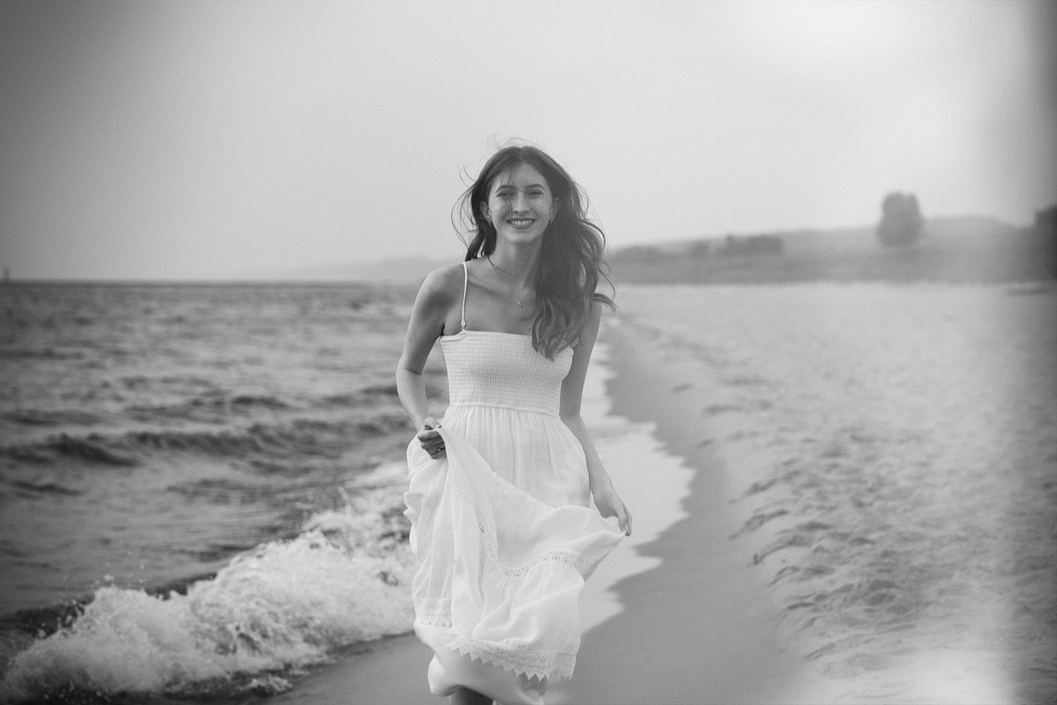 Ethereal black and white beach scene with flowing white dress.