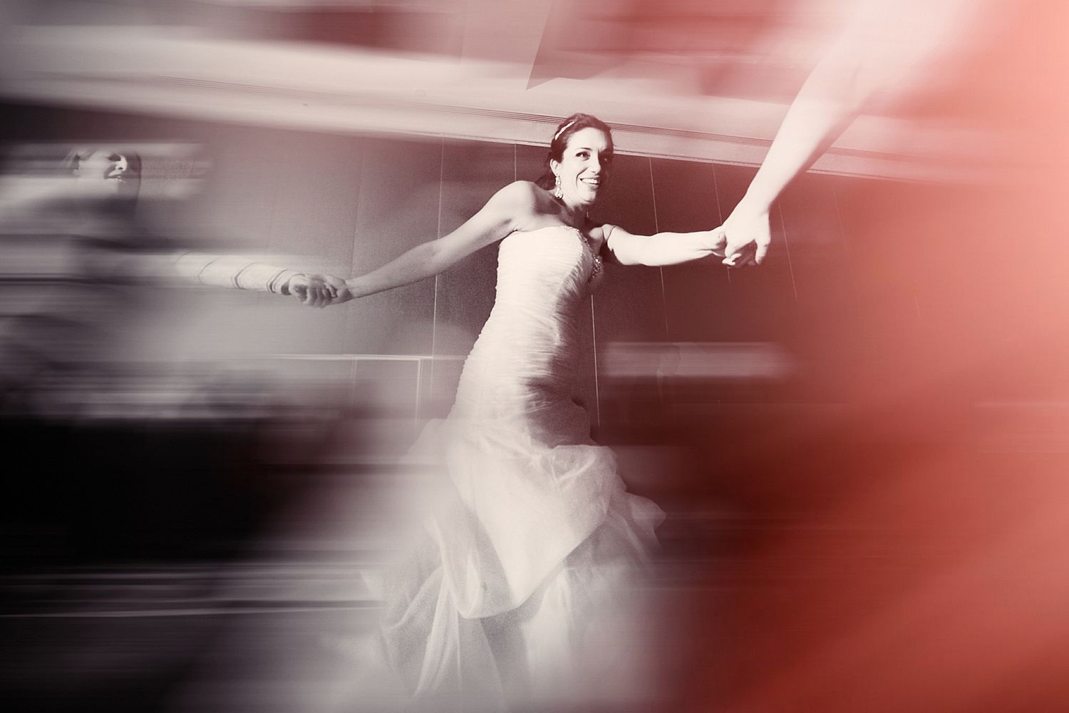 Motion blur photo of dancing at wedding reception with red lighting effects.