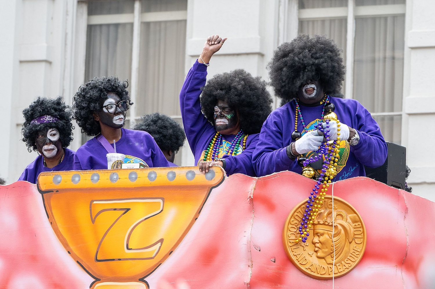 Colorful parade float with purple-clad performers and decorative elements moving through city streets.