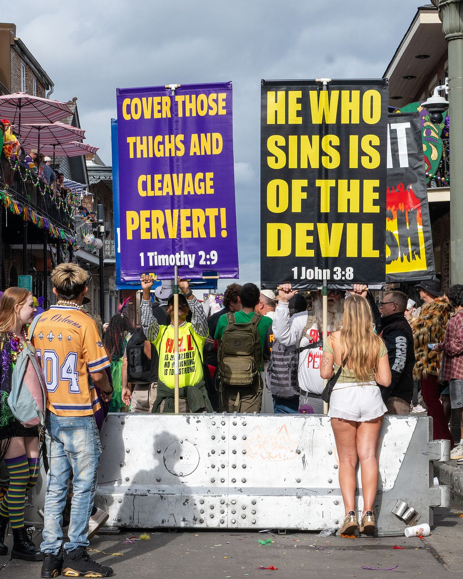 Religious protest signs lined up along a street during a public gathering.
