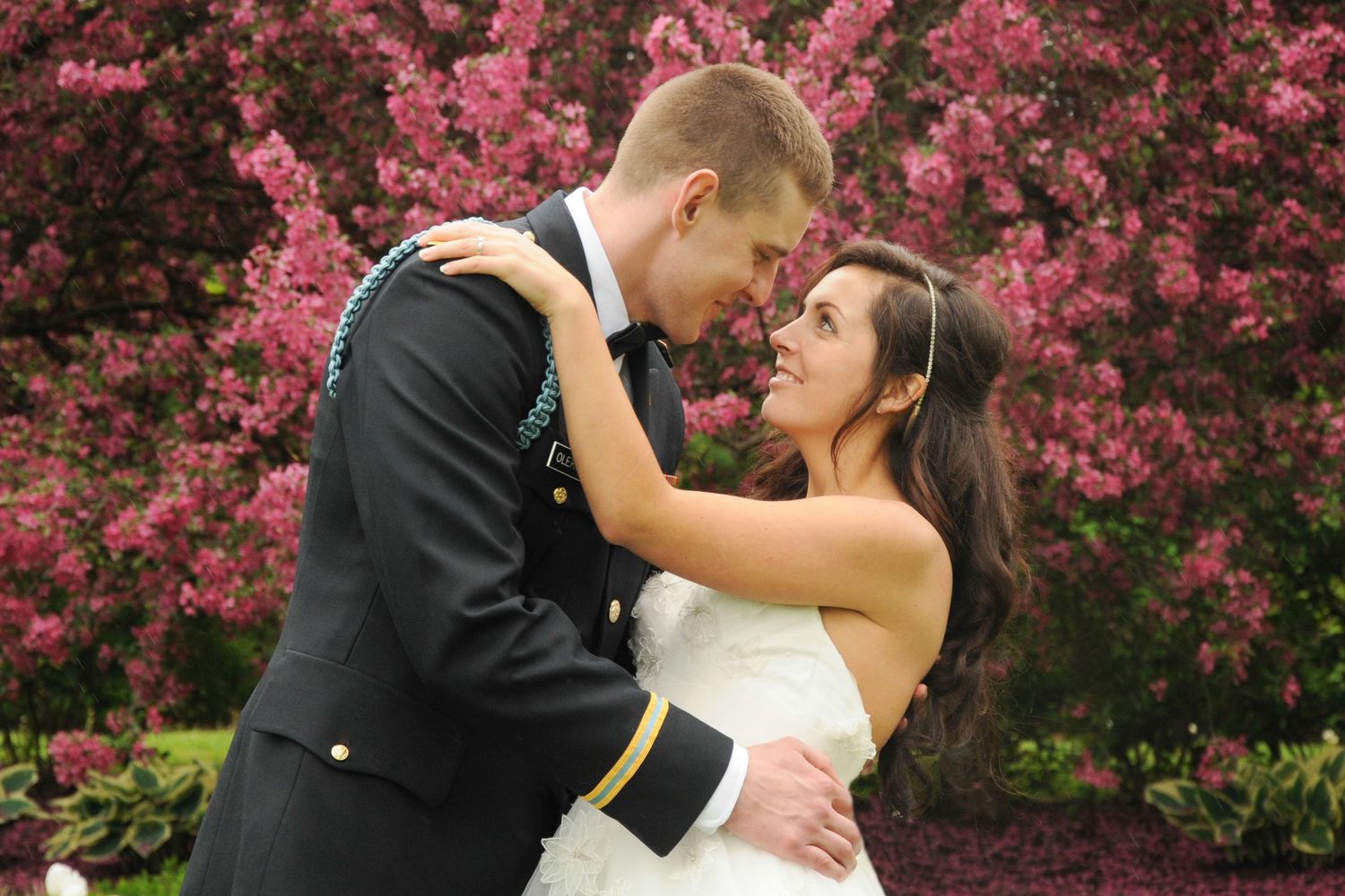 Romantic wedding portrait with couple embracing in front of blooming cherry blossoms.