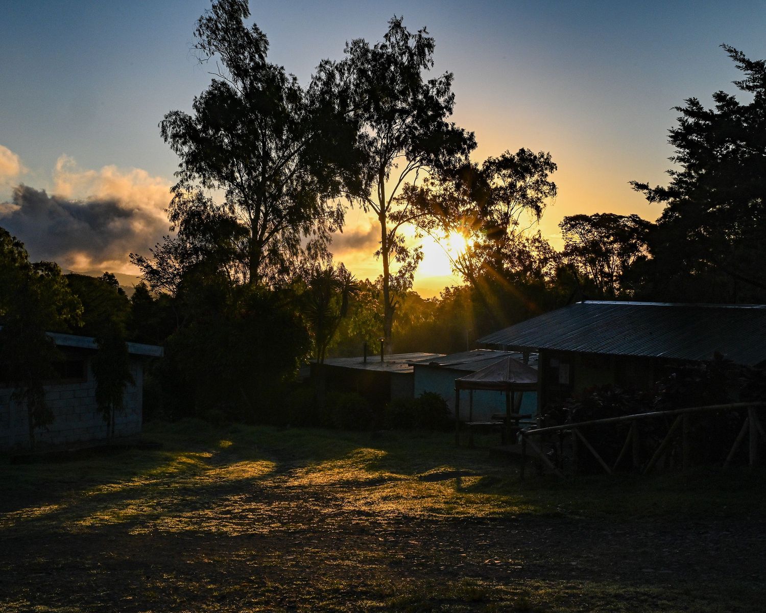 Panoramic sequence of a sunset over rural buildings with silhouetted trees against an orange sky.