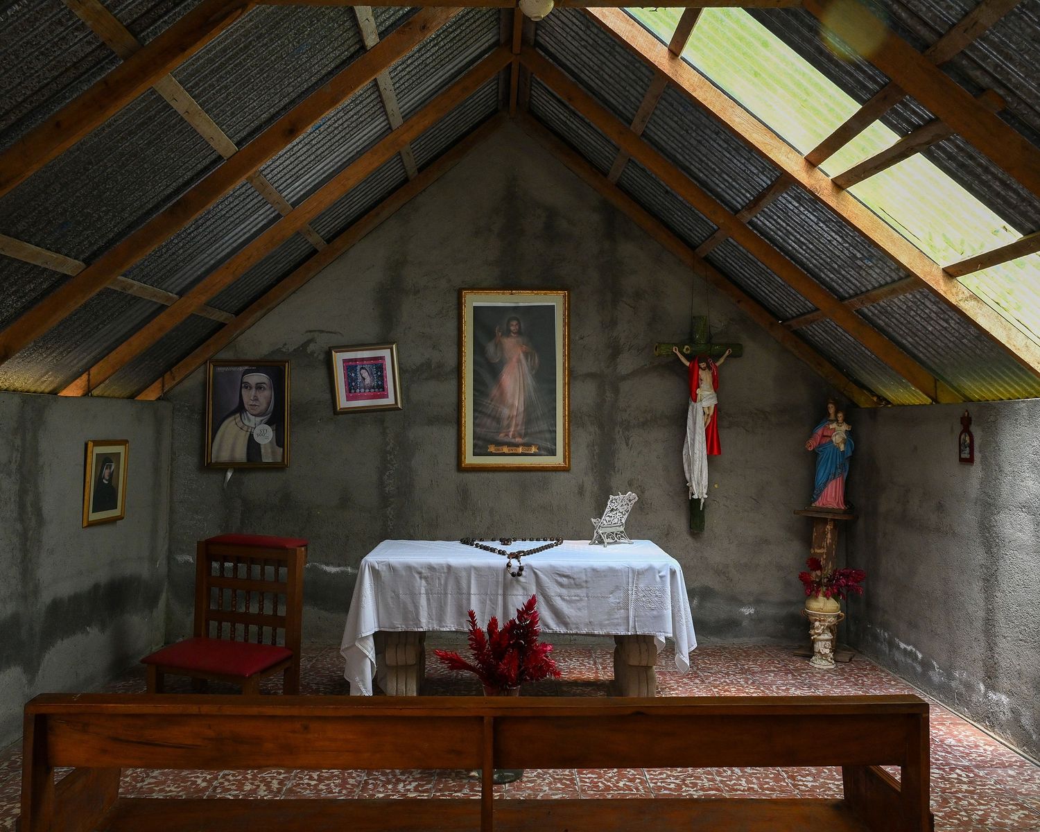 Interior view of a rustic chapel with wooden beams and religious artifacts on display.