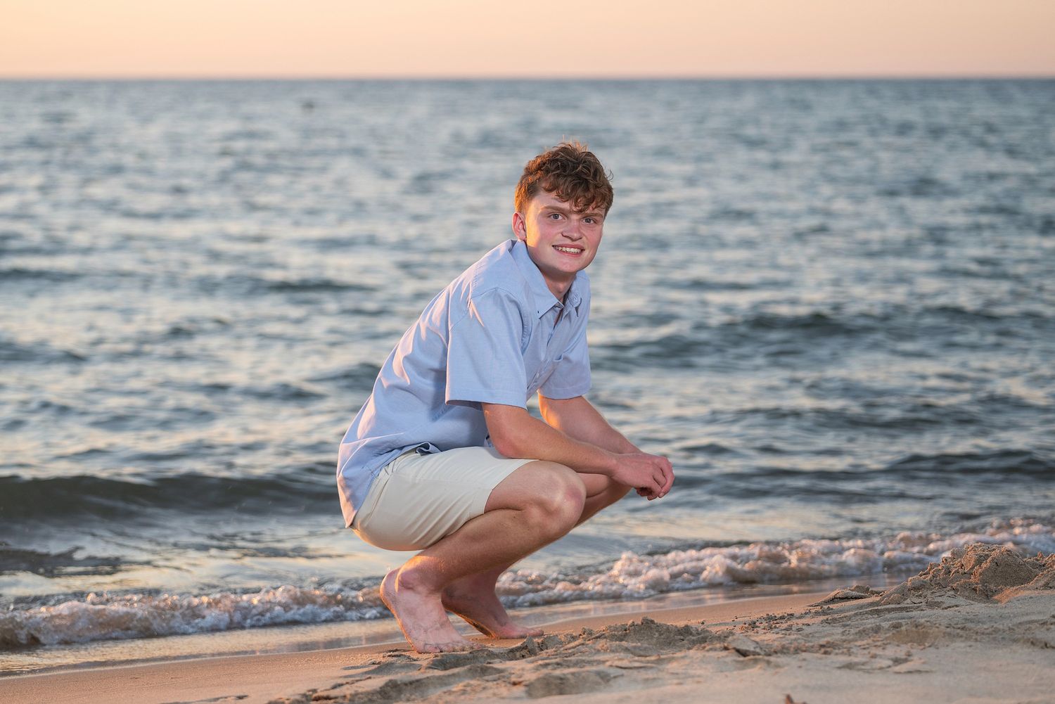 Person relaxing on beach during sunset with waves crashing nearby.