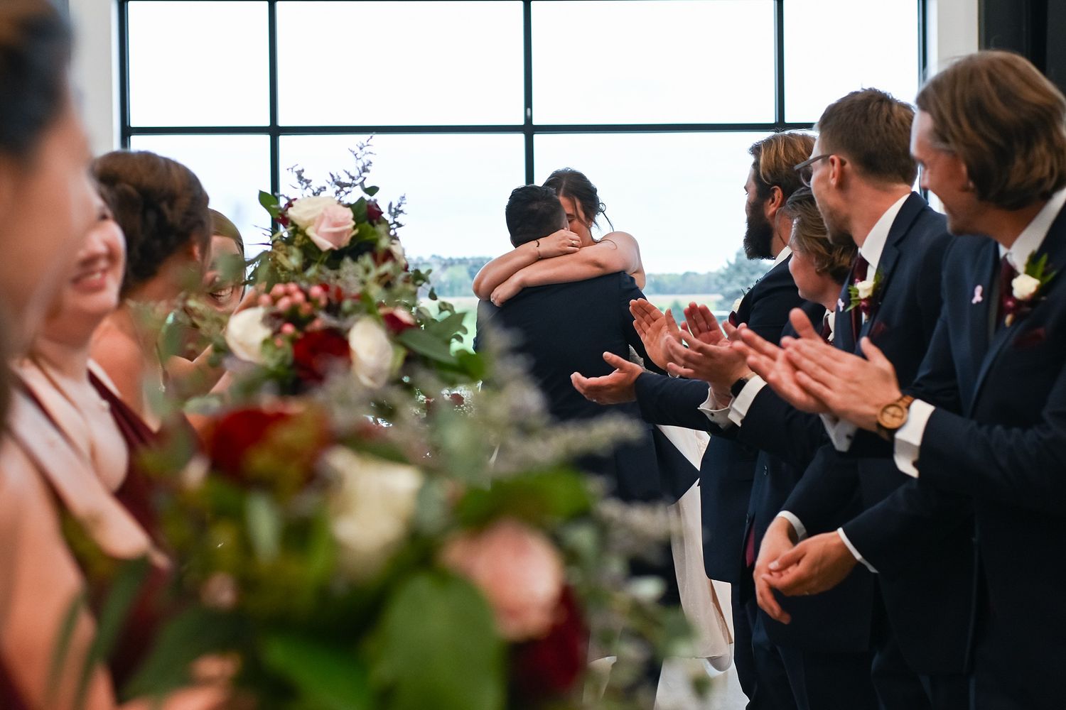 Wedding guests clapping as bride and groom share an emotional embrace during ceremony.