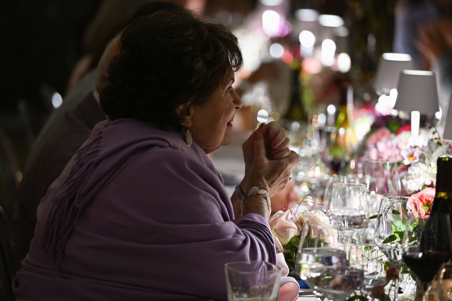 Diners seated at an elegant dinner table enjoy a formal dining experience with wine glasses and ambient lighting.