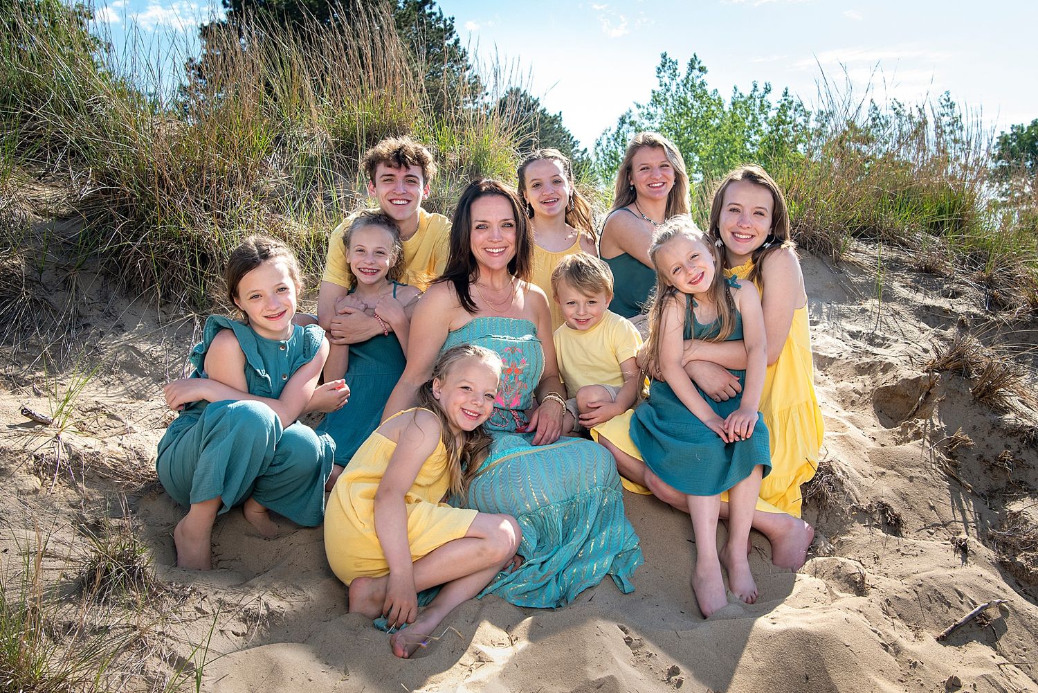 Group relaxing together on a sandy beach wearing coordinated teal and yellow outfits.