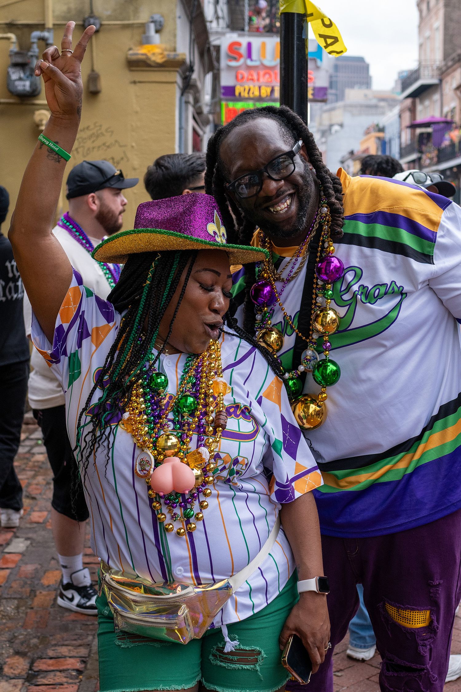 Revelers in Mardi Gras colors of purple, green and gold celebrate with beads and festive attire.