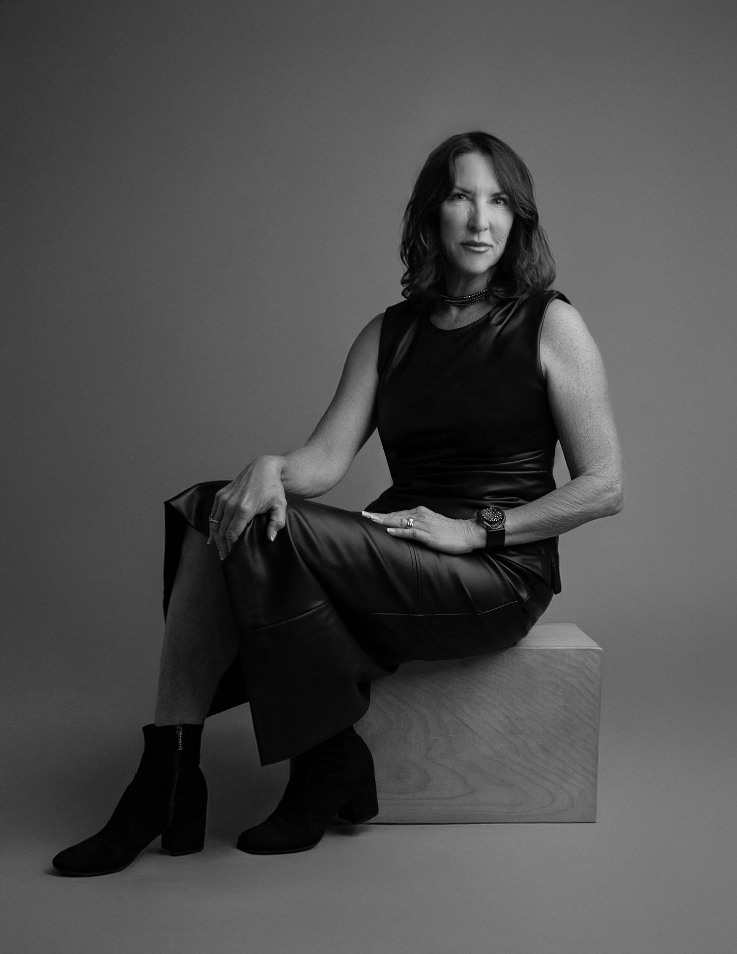 Black and white fashion photo series showing a person in dark clothing posing on a light colored floor against a plain backdrop.