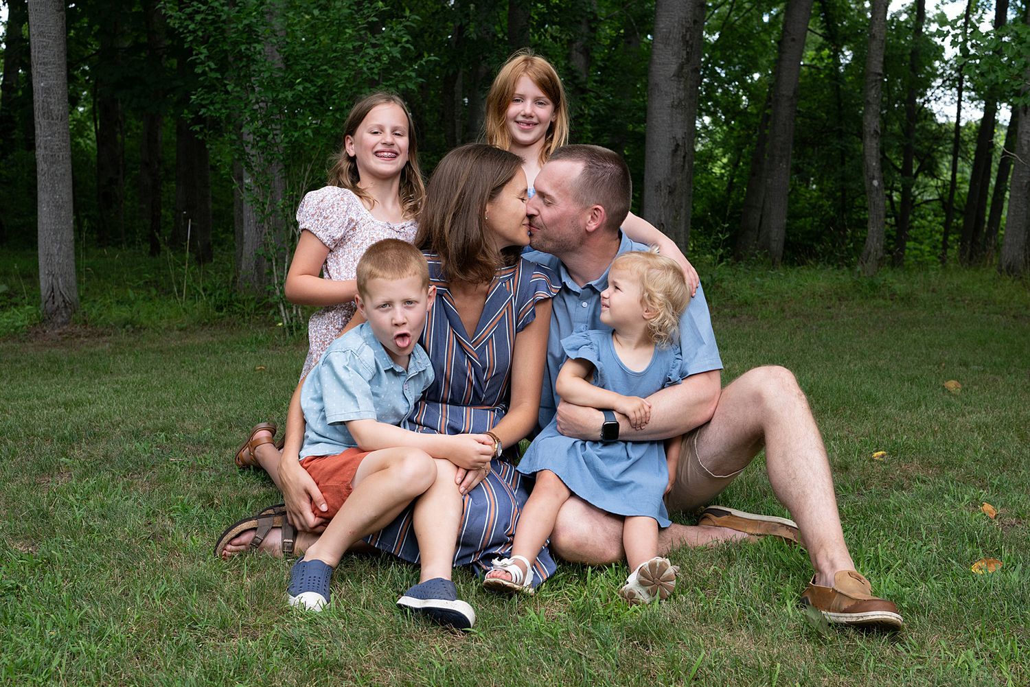 Family relaxing together on grass during an outdoor summer photo session.
