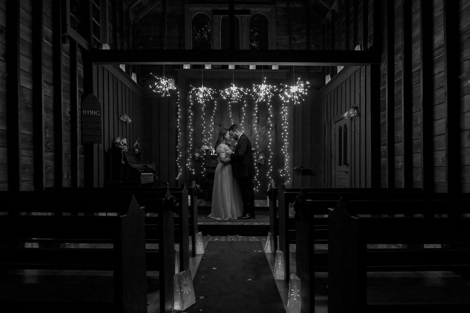 Elegant indoor wedding ceremony venue with dramatic lighting and hanging chandeliers.