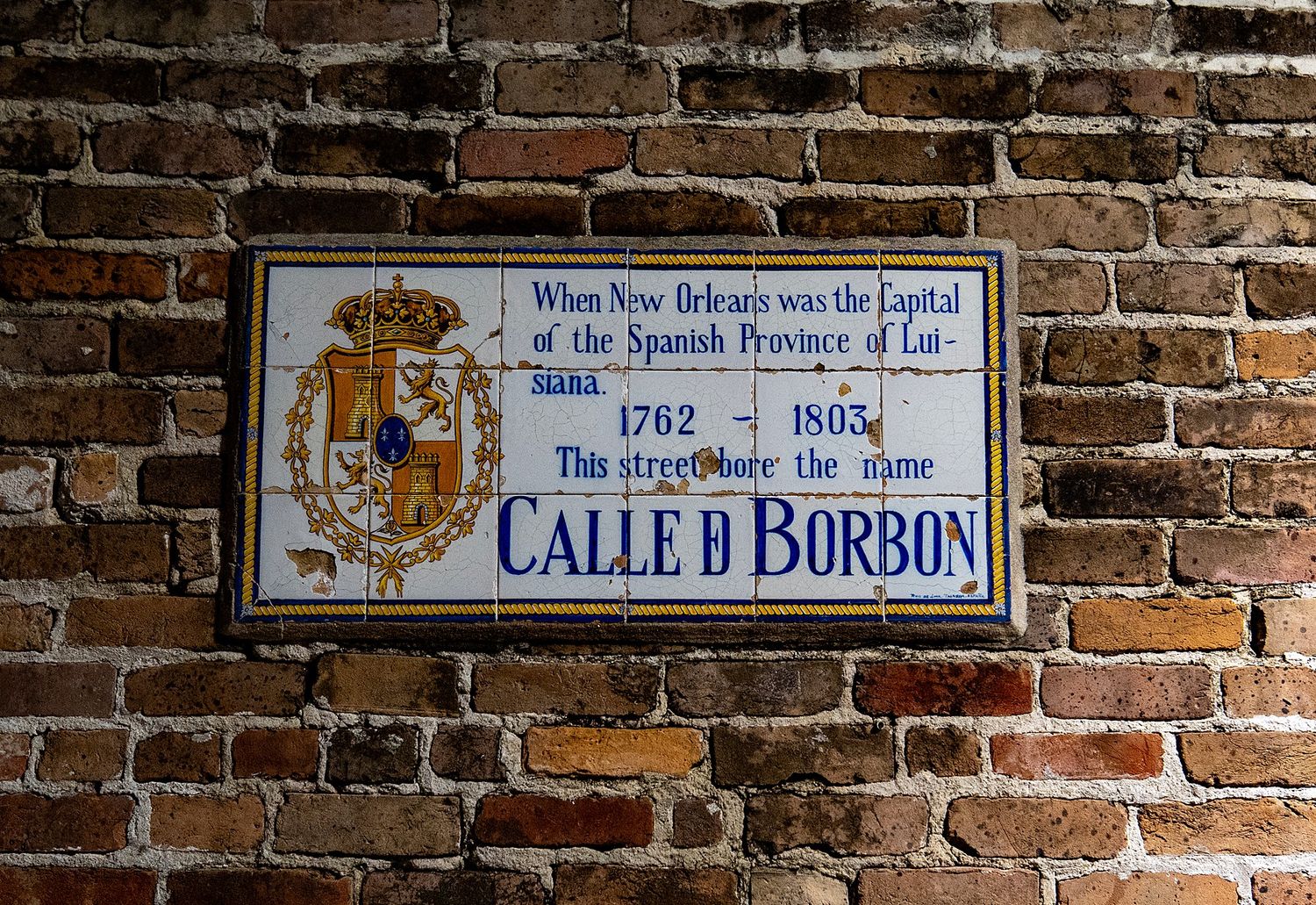 Historic Bourbon Street sign and brick wall showing the street's Spanish colonial heritage from 1762.